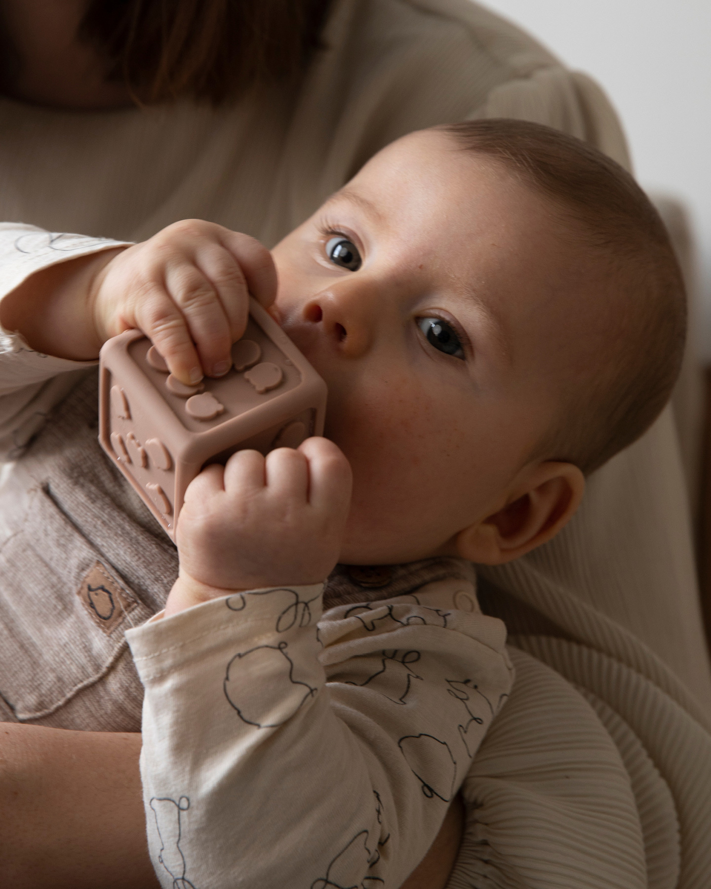 Baby hält großen Spielzeugwürfel in den Händen