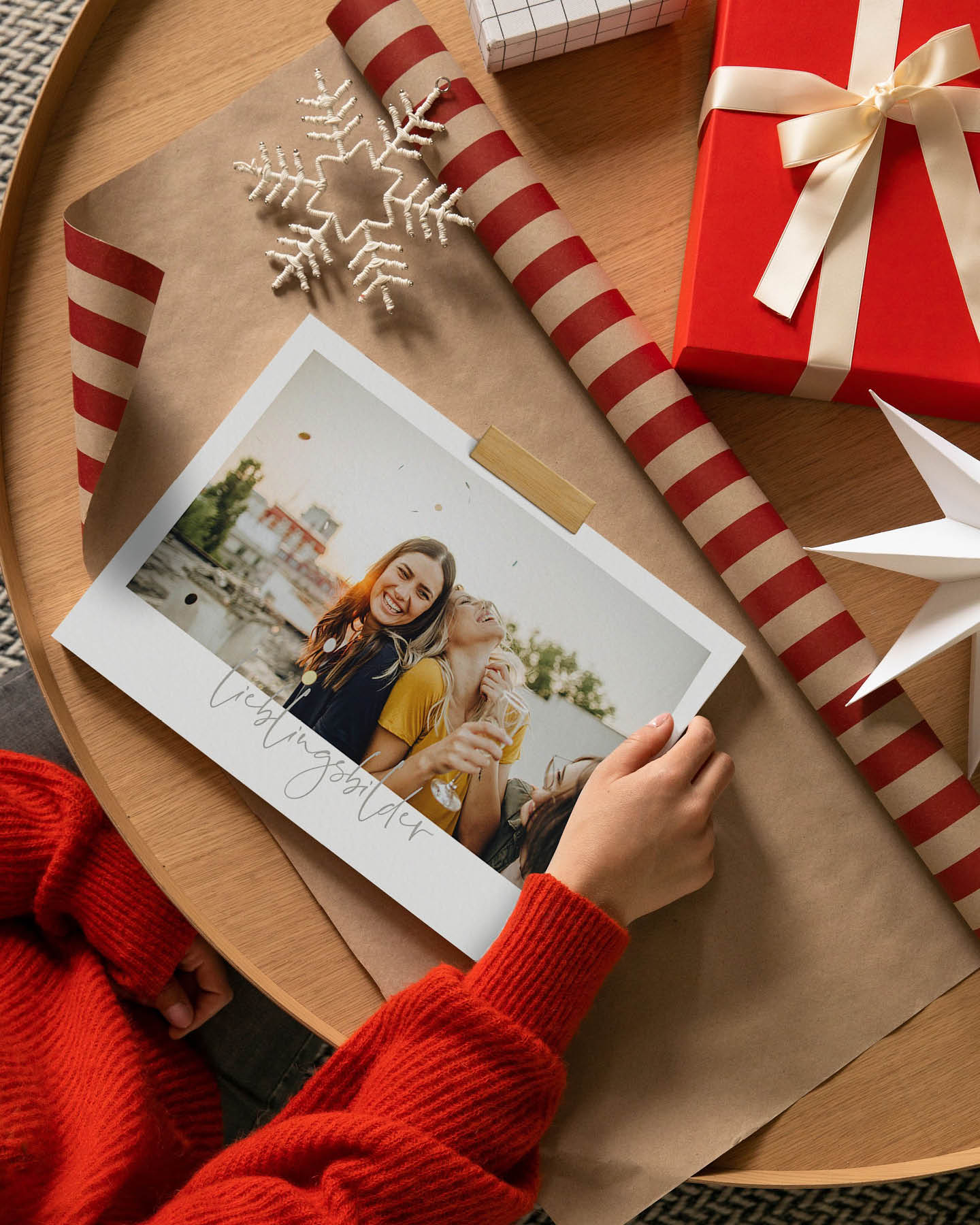 Frau im roten Pullover hält Fotokalender in den Händen.