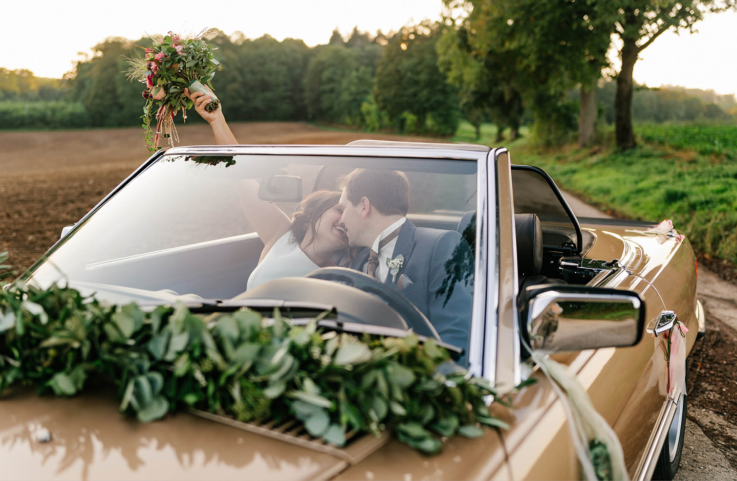 frisch gebackenes Hochzeitspaar sitzt im Auto auf dem Weg zur Feierlocation.