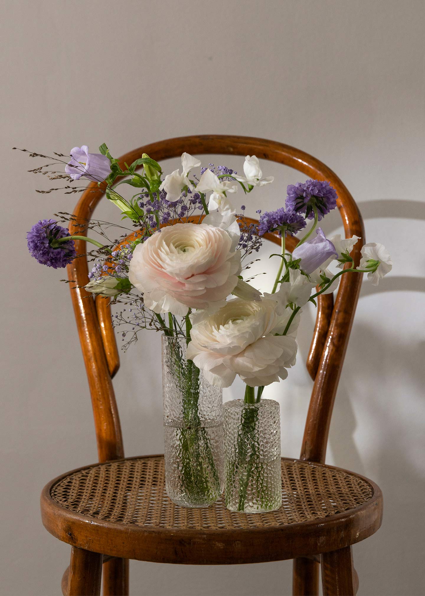 Vasen aus Glas mit üppigen Blumen gefüllt auf dem Hochzeitsstuhl