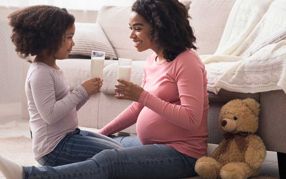 Schwangere trinkt Milch mit Tochter