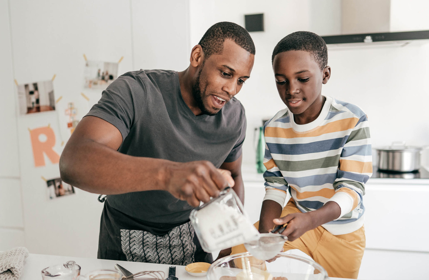 Vater und Sohn stehen gemeinsam in der Küche und backen. 