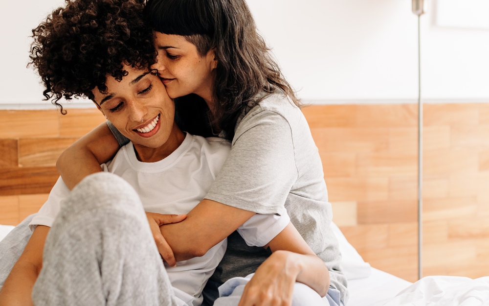 Zwei Frauen kuscheln auf Bett