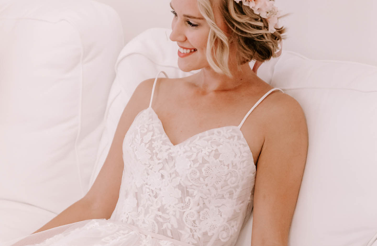 Frau in einem Hochzeitskleid sitzt auf einer weißen Couch.