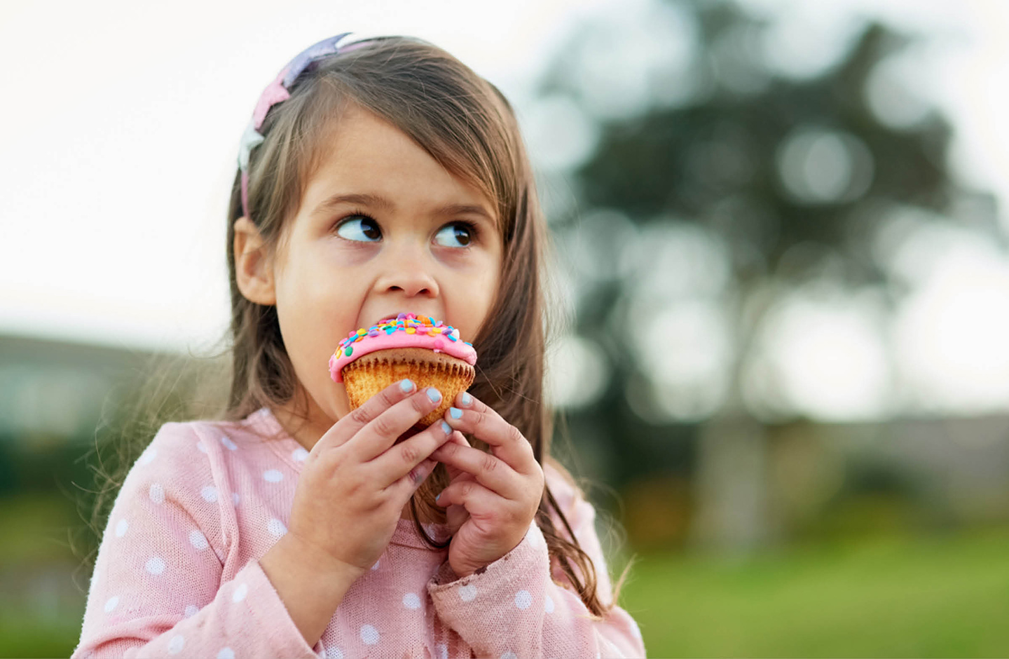 kleines Mädchen beißt beherzt in einen Cupcake.. 