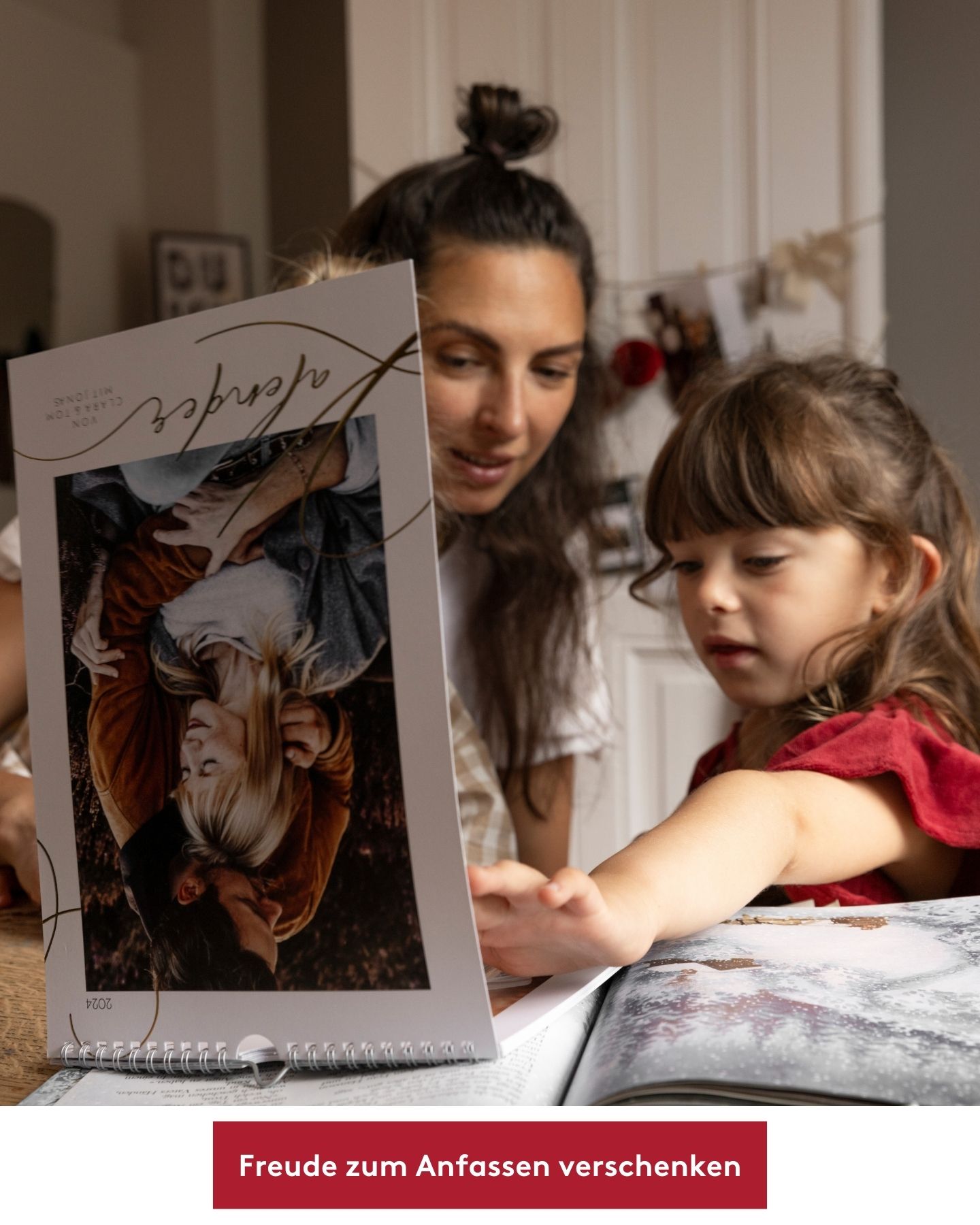 Frau und Kind blättern durch Wandkalender mit vielen Familienfotos.