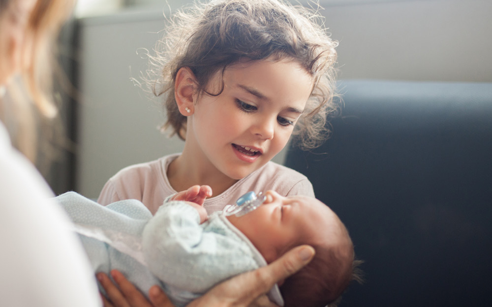 Schwester bewundert neugeborenes Baby