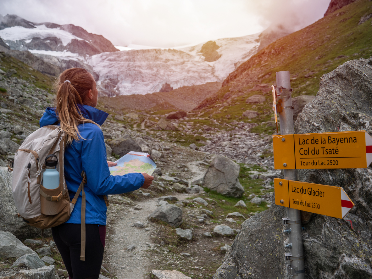 Frau steht vor Wegweisern beim Wandern