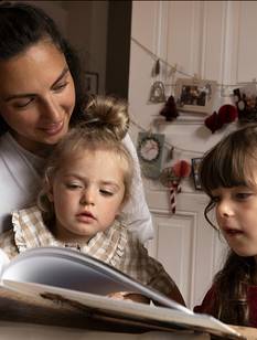 Mutter liest ihren kleinen Töchtern in der Adventszeit ene Geschichte vor