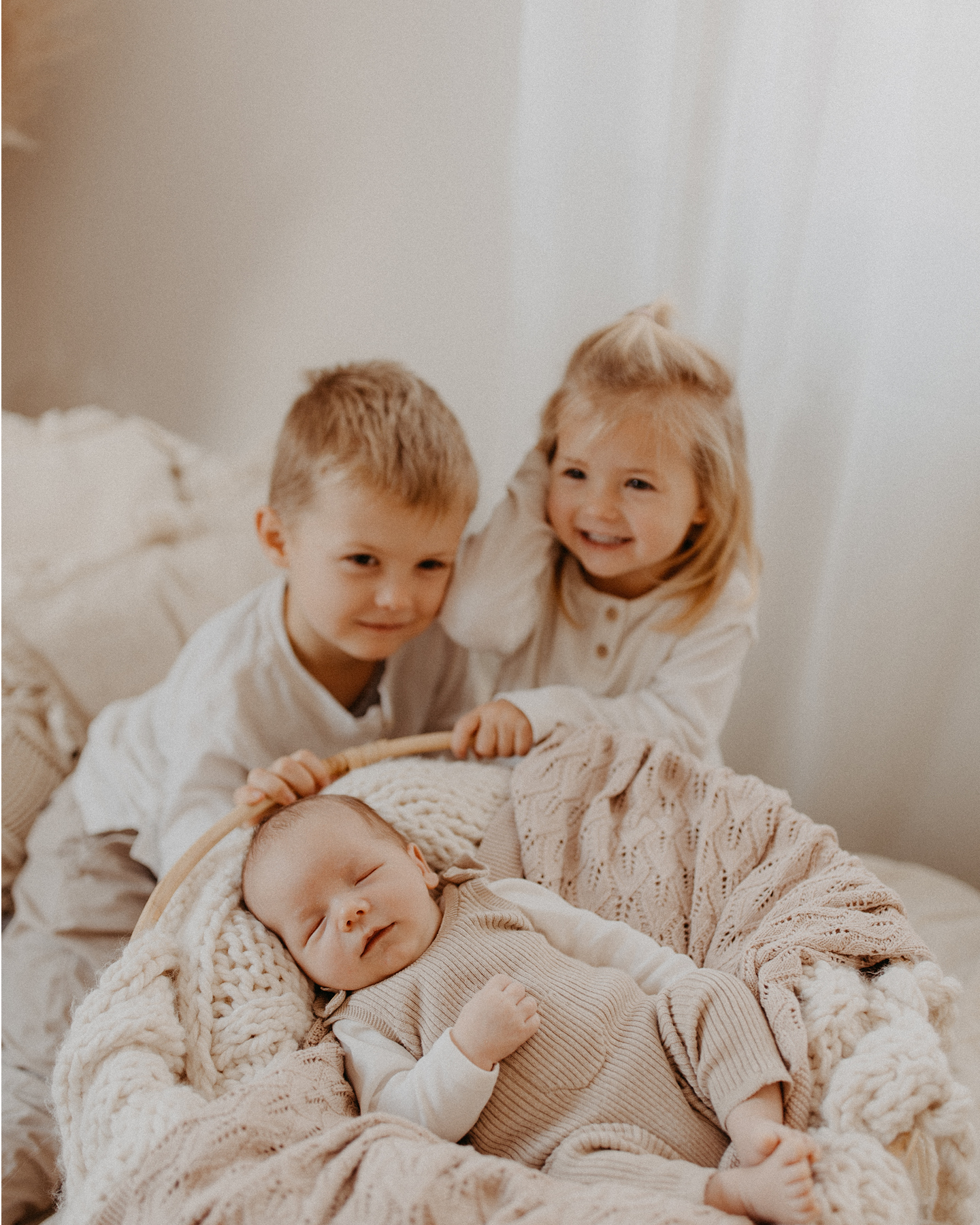 Schlafendes Baby im Babykorb mit Bruder und Schwester 