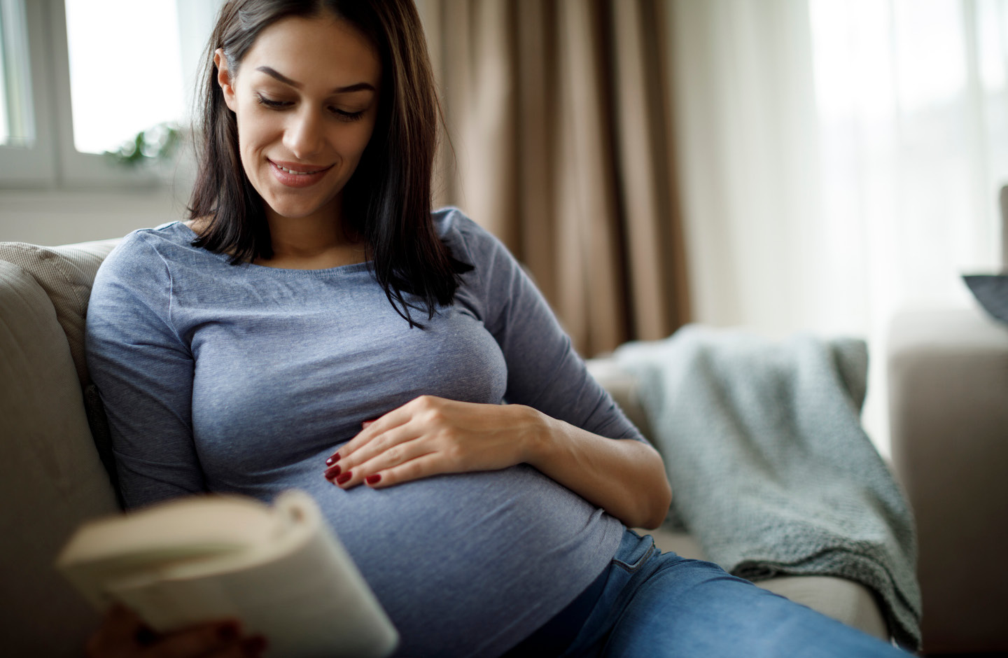 Schwangere mit Babybauch entspannt beim Lesen