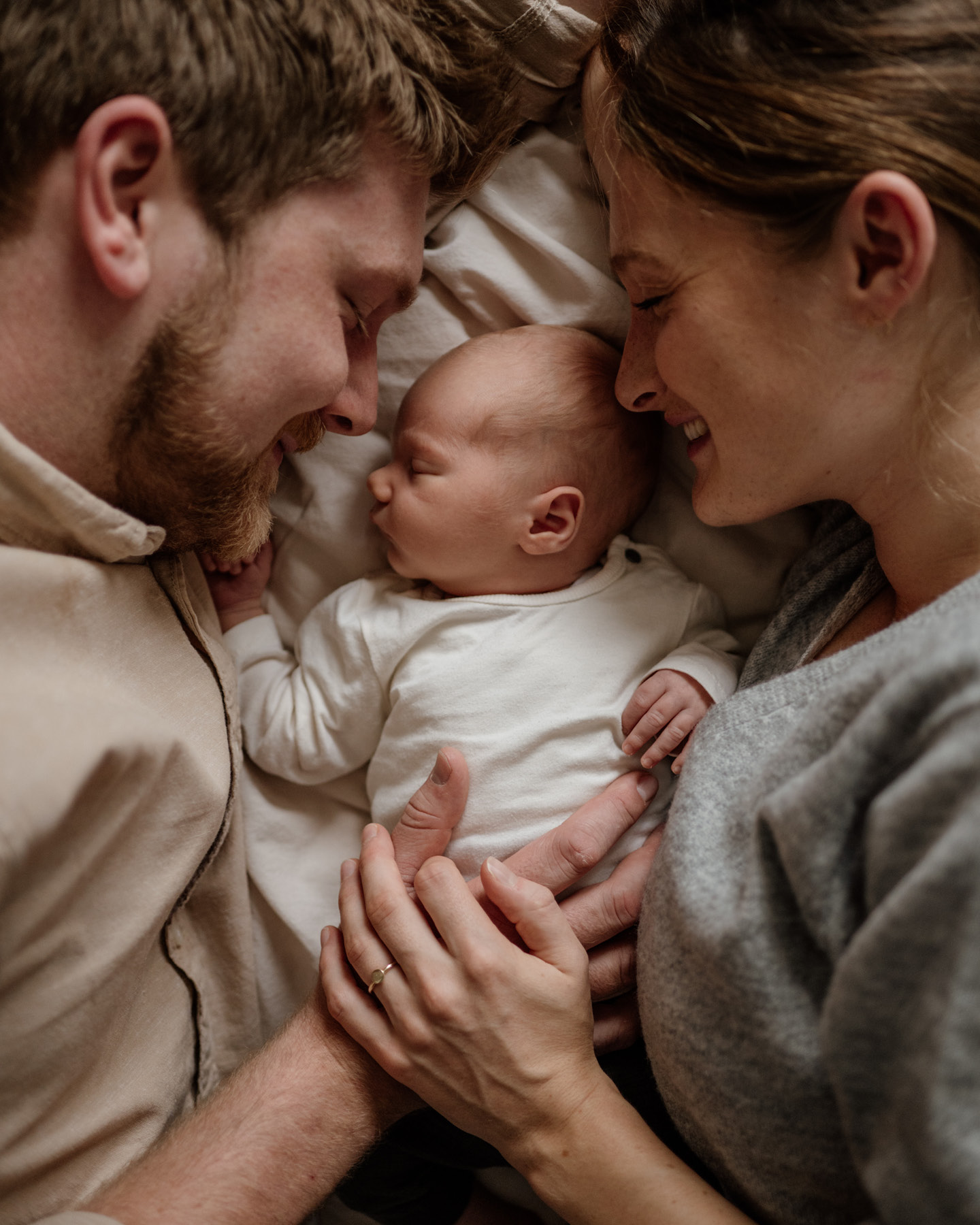 Glückliche Eltern kuscheln mit neugeborenem Baby