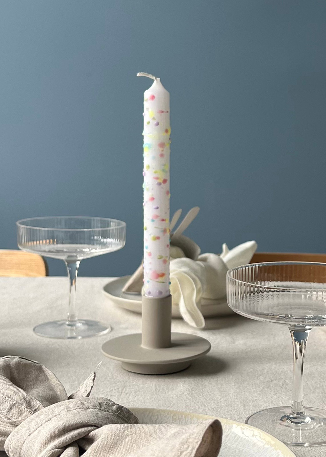 Fertiges DIY: Kerze mit Sprenkeln in bunten Farben auf dem Tisch