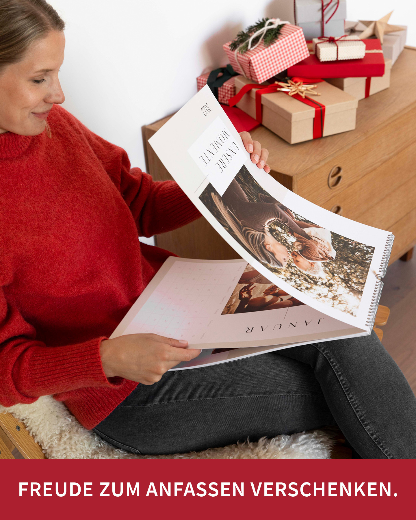 Frau im roten Pullover blättert durch Wandkalender mit vielen Familienfotos.
