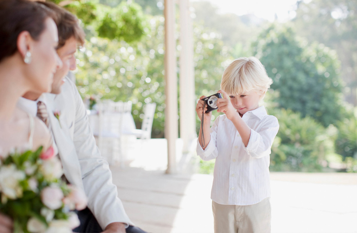 Kleiner Junge beschäftigt schieß Bilder vom Brautpaar mit einer kleinen Kamera. 