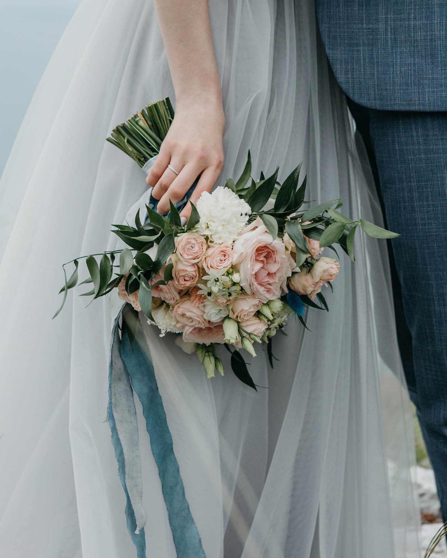 Brautstrauß aus Rosen in Weiß und Rosa vor hellblauem Kleid