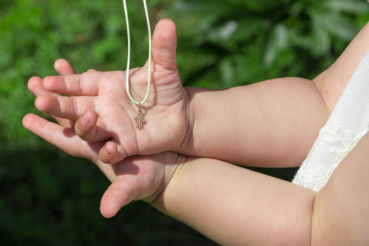 Kinderhände halten eine Kreuzkette