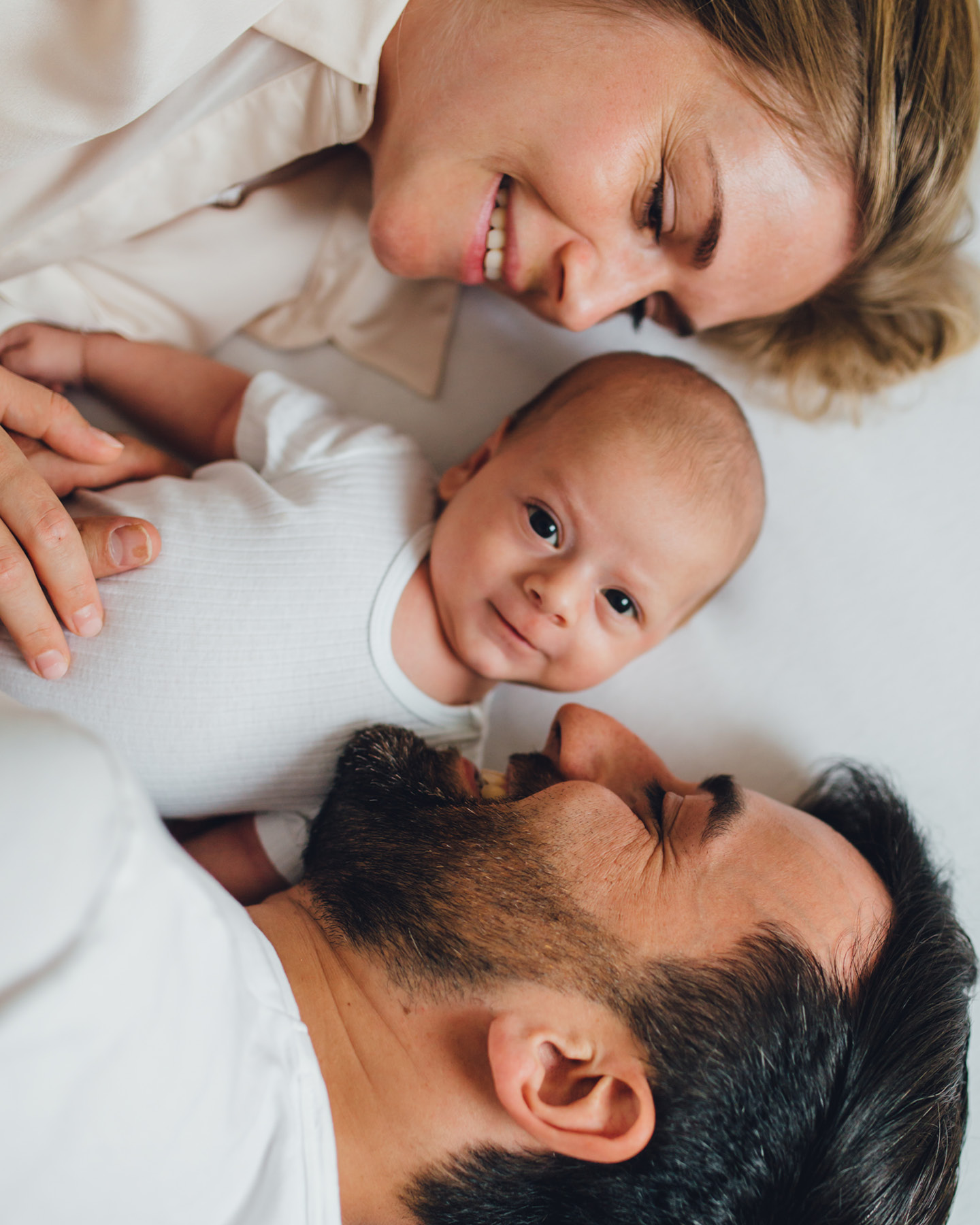 Eltern im Bett mit ihrem lächelnden Baby in der Mitte