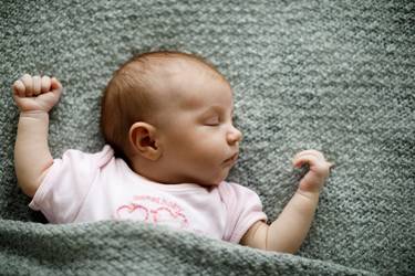 Schlafendes neugeborenes Baby mit russischen Mädchennamenauf salbeigrüner Wolldecke