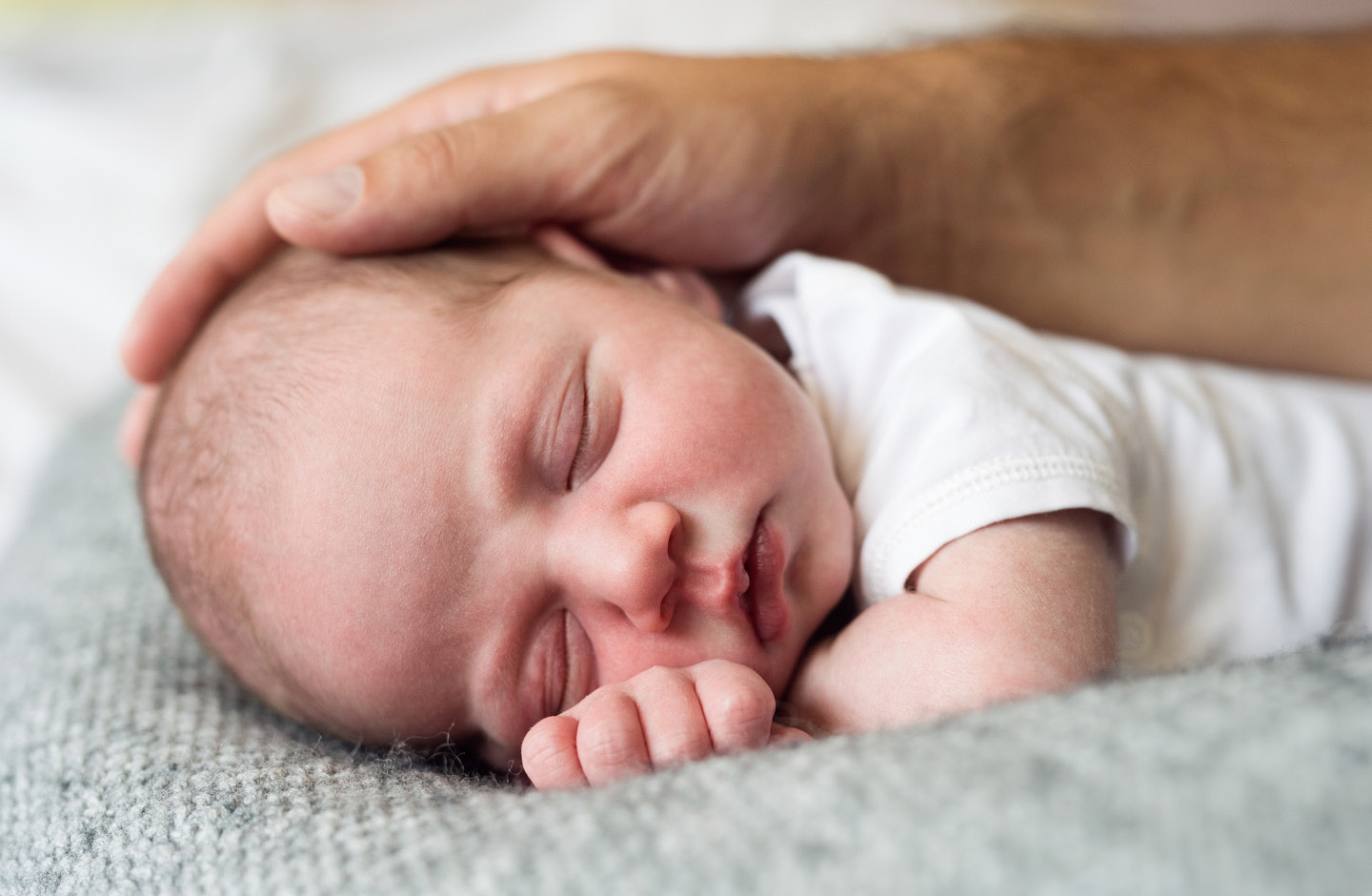 Vater legt zärtlich seine Hand auf schlafendes Baby