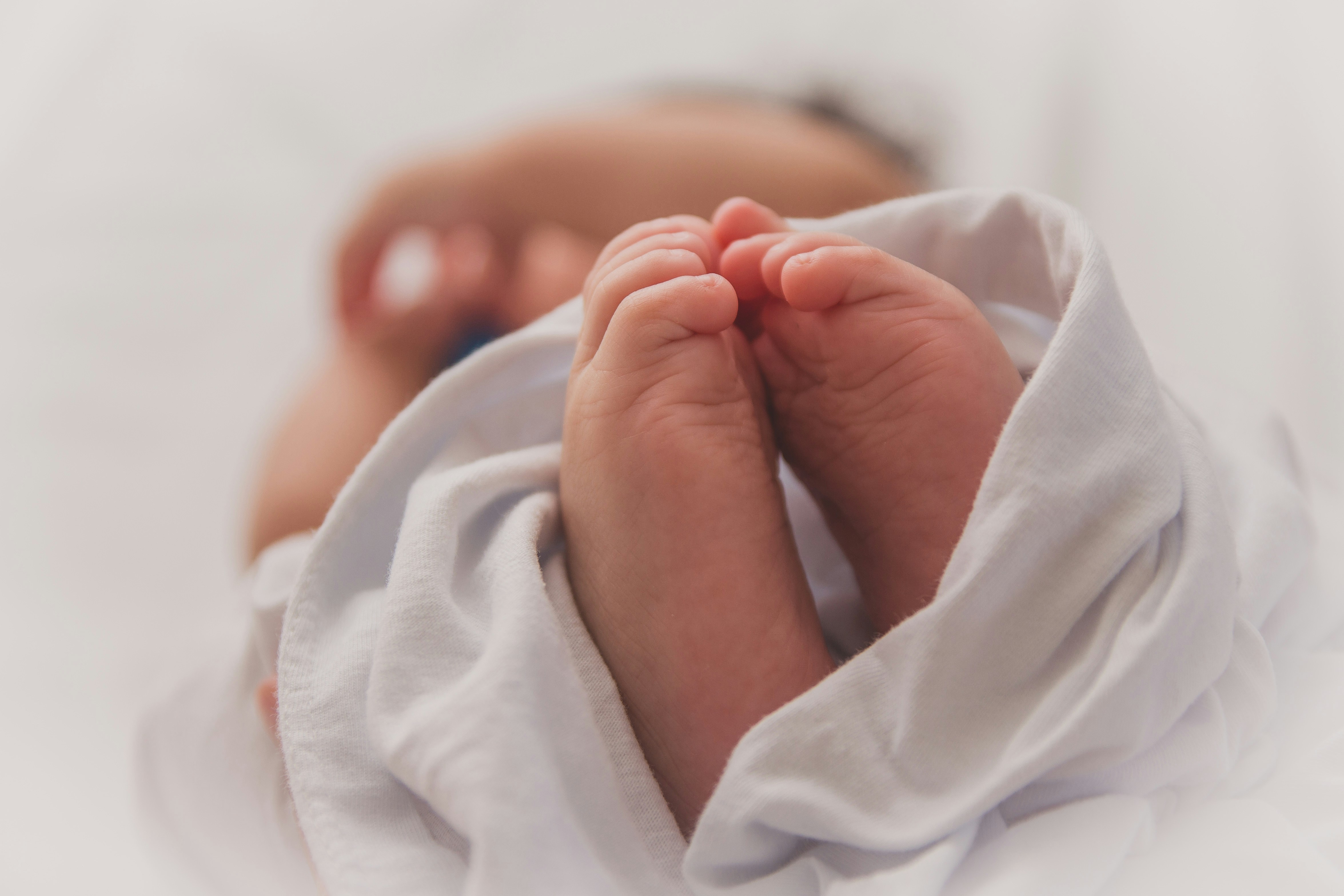 Die Füße eines in einem weißen Tuch eingewickelten Babys.