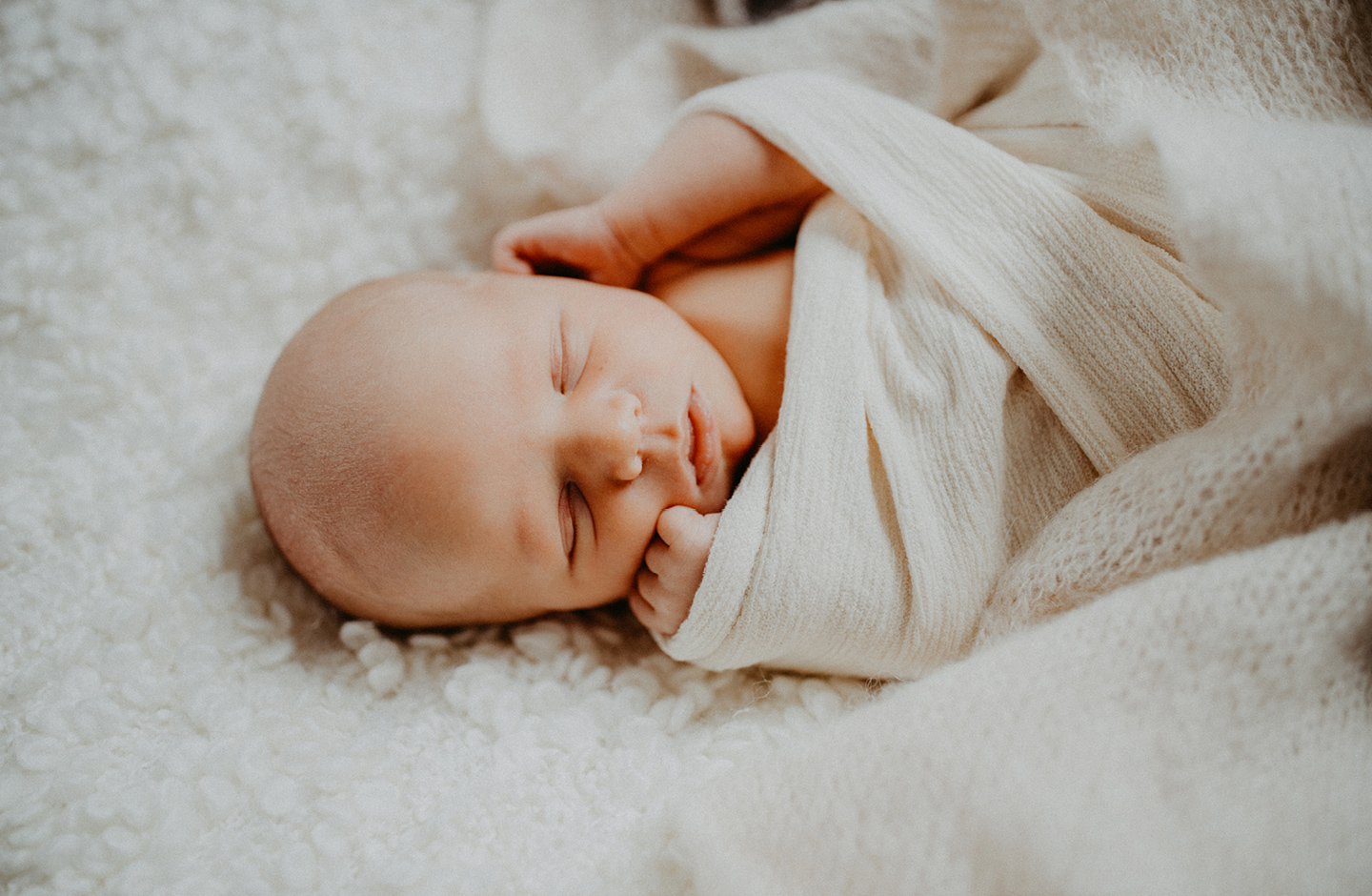 Neugebornes ist in weiße Decken eingekuschelt und schläft nach der Geburt mit Geburtsplan.