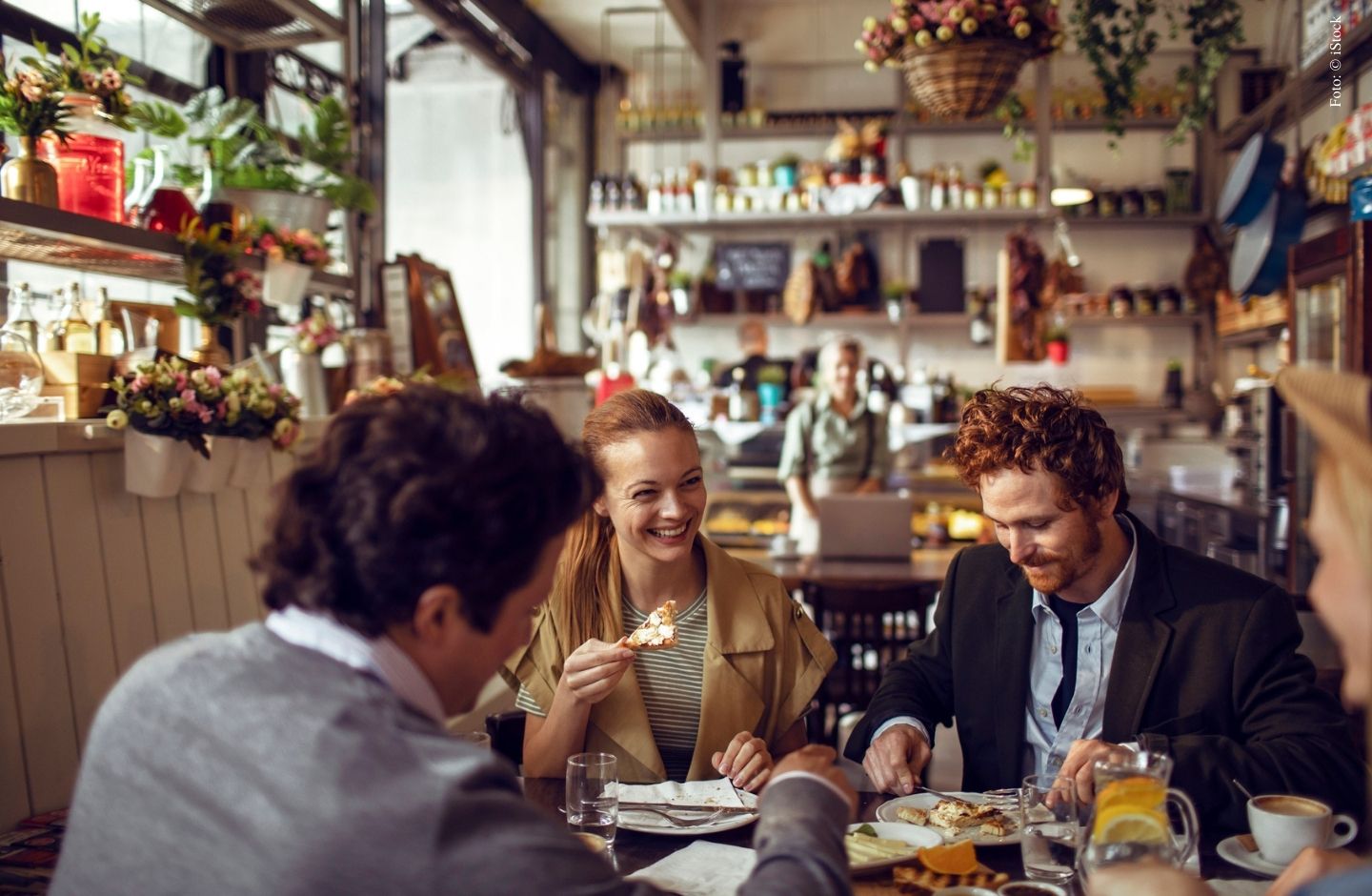 Personen sitzen an Tisch und essen.