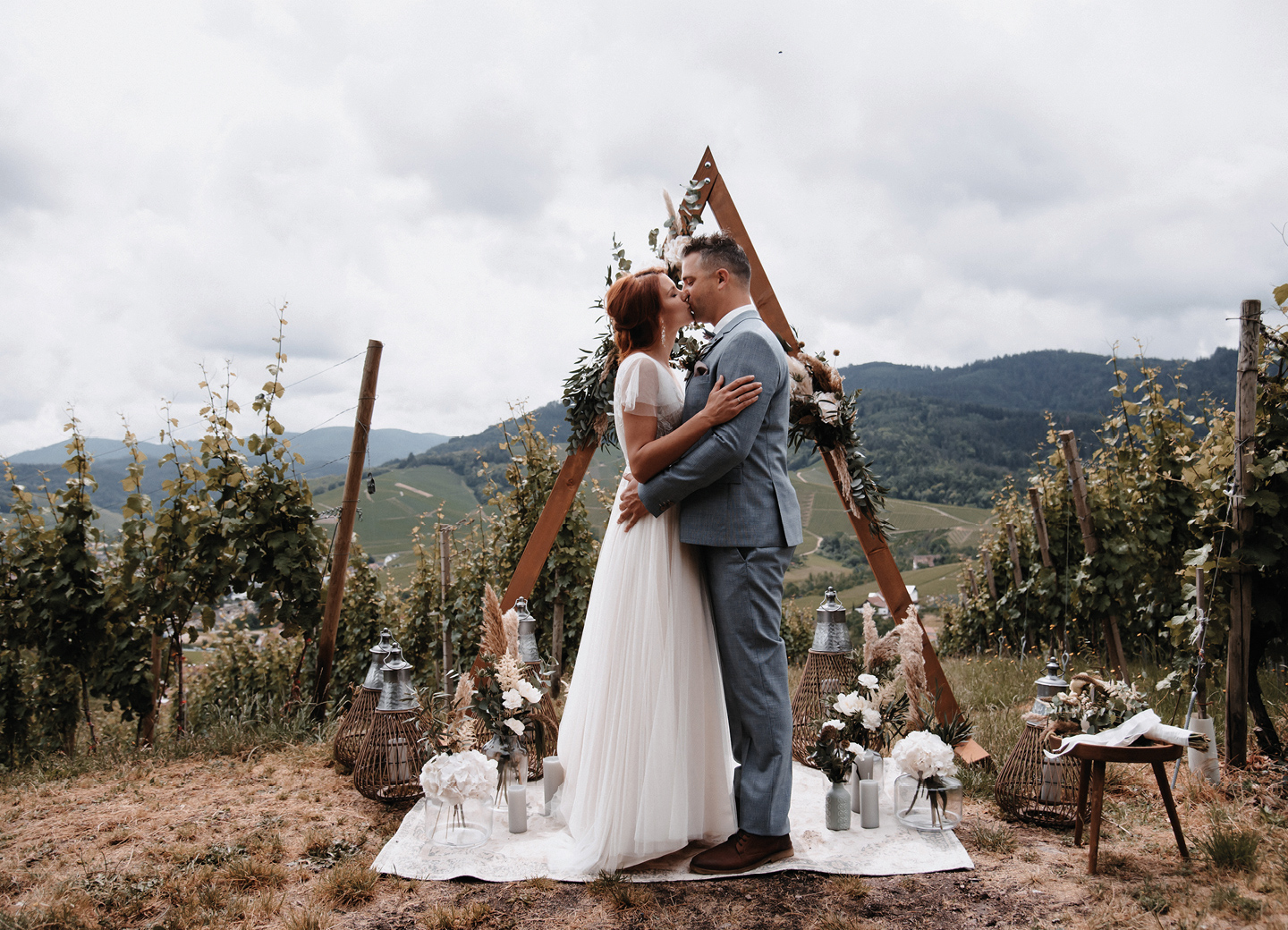 Brautpaar küsst sich zum Ja Wort vor Boho Traubogen und Deko aus Pampasgras: Checkliste zur Hochzeit.