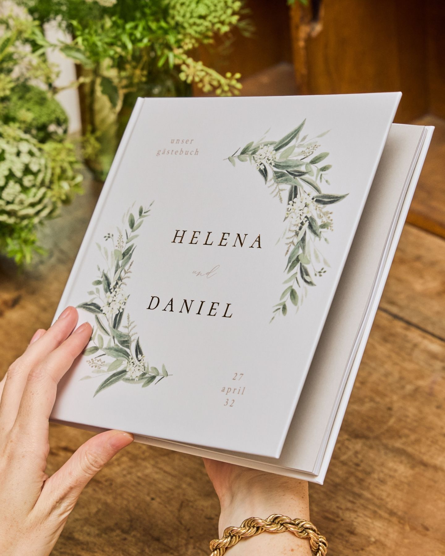 weibliche Hände mit Gästebuch im Greenery-Stil