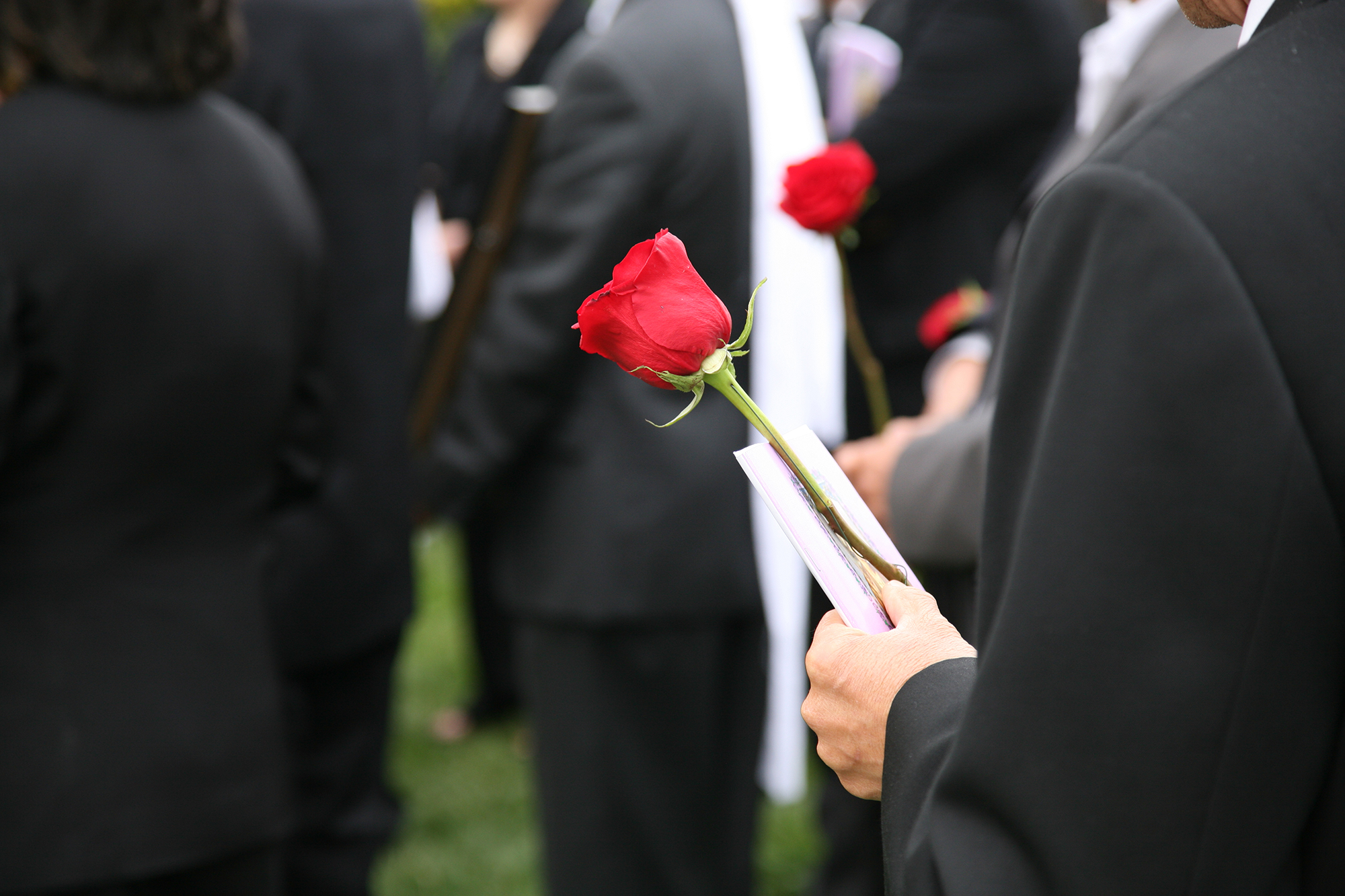 Checkliste Trauerfall: Mann hält Rose auf Beerdigung