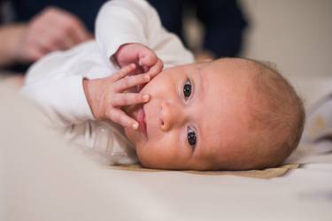 Baby in weißem Jäckchen auf dem Wickeltisch