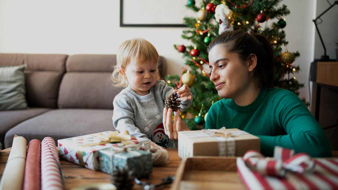 Mama verpackt mit ihrem Kind Weihnachtsgeschenke