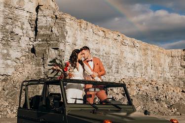 Das Hochzeitspaar befindet sich auf einem Geländewagen und schaut sich verliebt in die Augen. Im Hintergrund ist die Location - ein Steinbruch - zu sehen