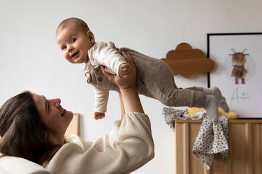 Mutter hebt ihr lächelndes Baby hoch