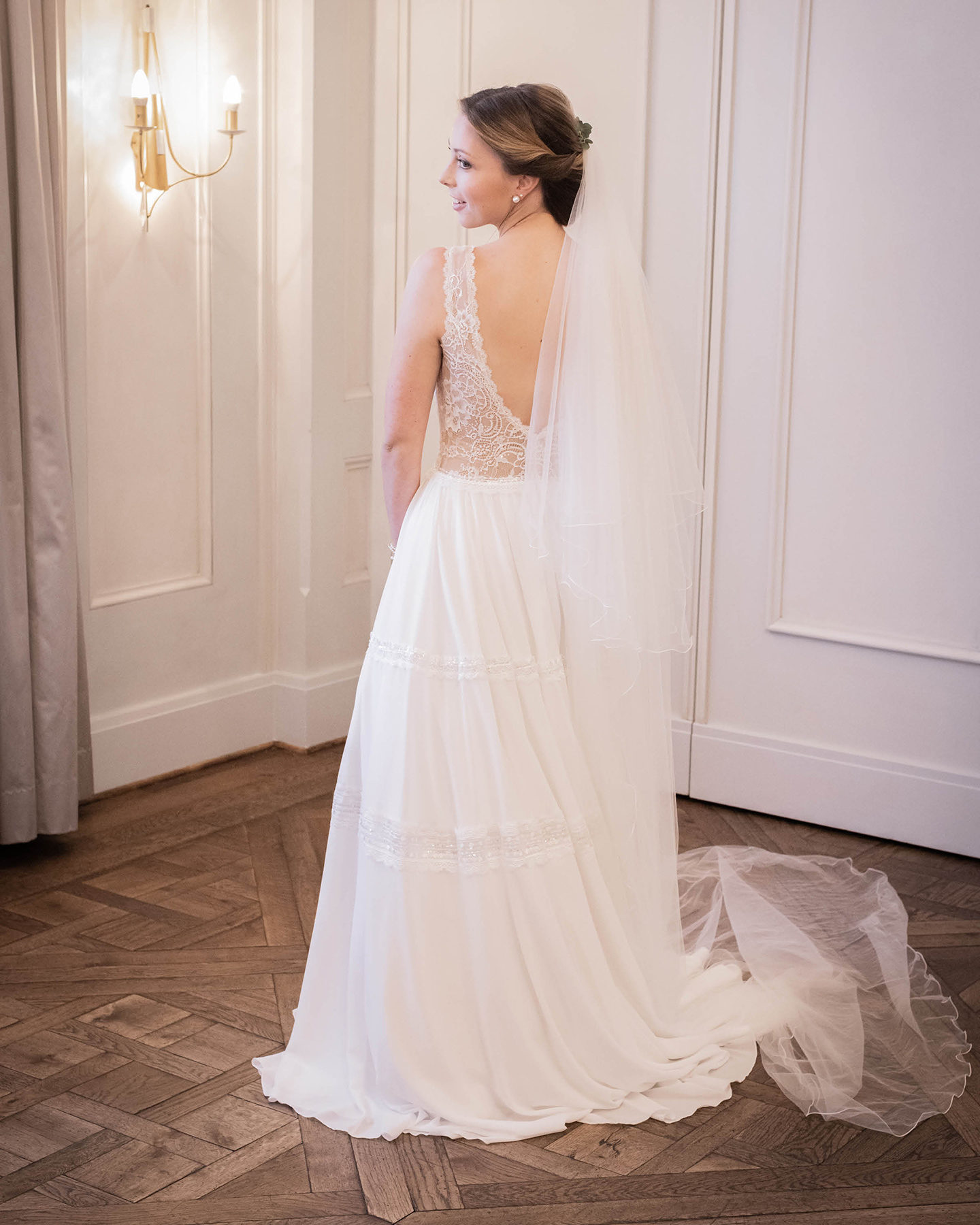 Foto von der Braut in ihrem langen weißen Hochzeitskleid mit tiefem Rückenausschnitt und einem langen Schleier