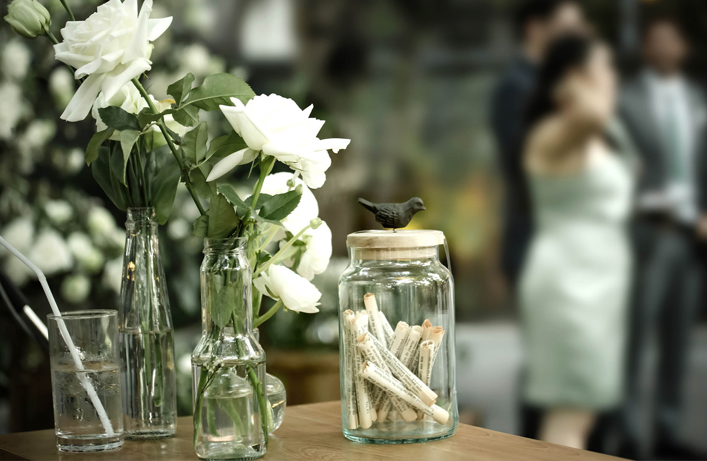 Hochzeitstisch dekoriert mit einem alten Glas in dem eingerollte Zettelchen liegen.