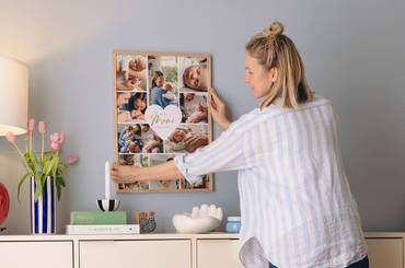 Junge Mutter hängt ihr Muttertagsgeschenk, eine gerahmte Cllage, an die Wand