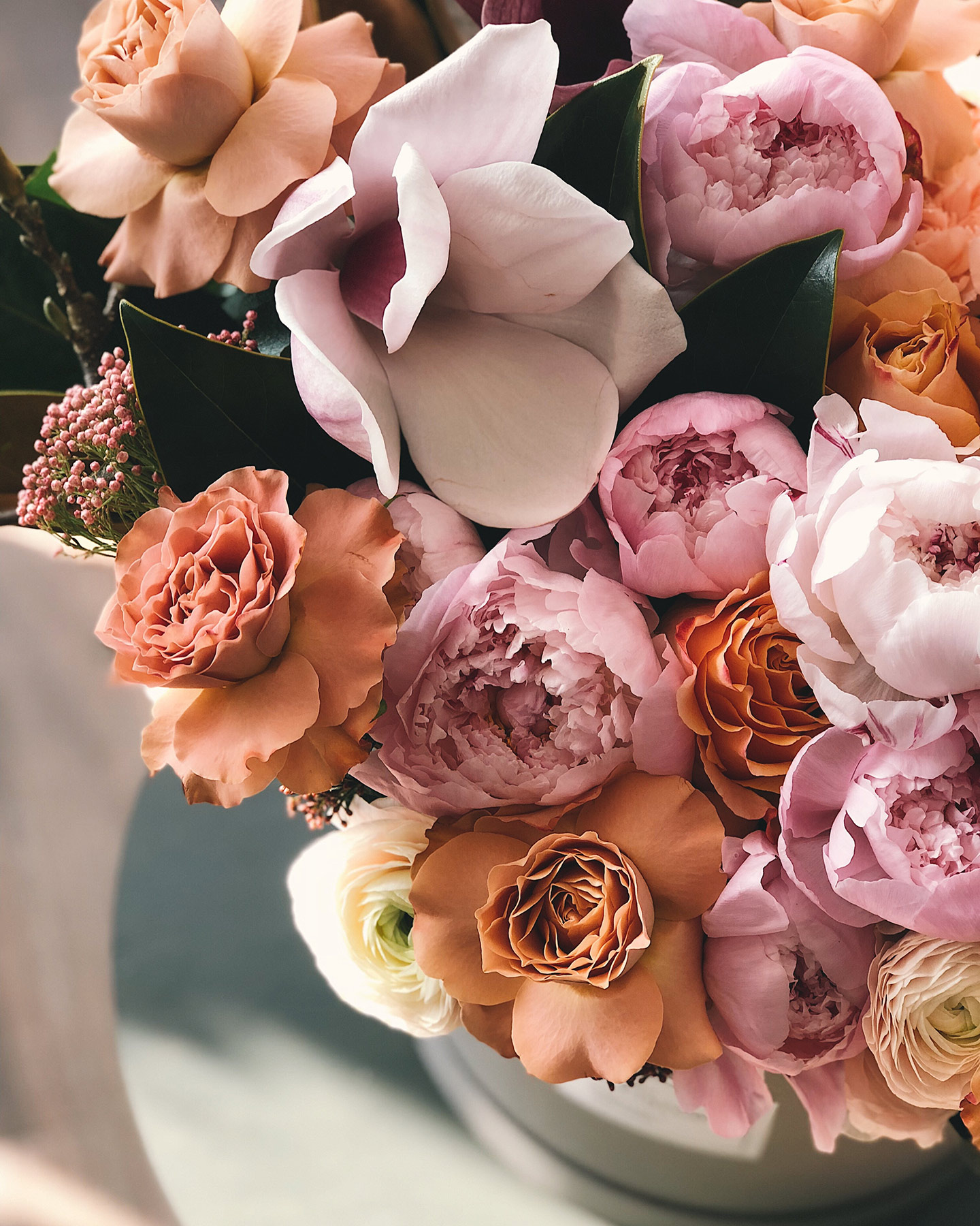 Blumenbpuquet in Rosa, Orange und weiteren Pastelligen Frühlingsfarben auf einem Tisch drapiert.