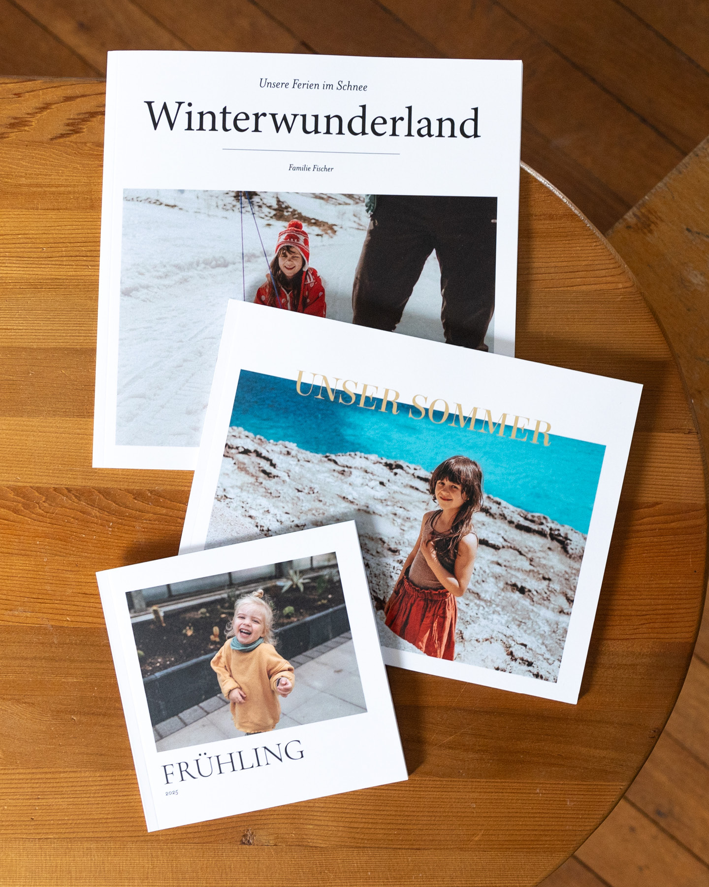 Drei Fotobücher in verschiedenen Formaten auf einem Holztisch