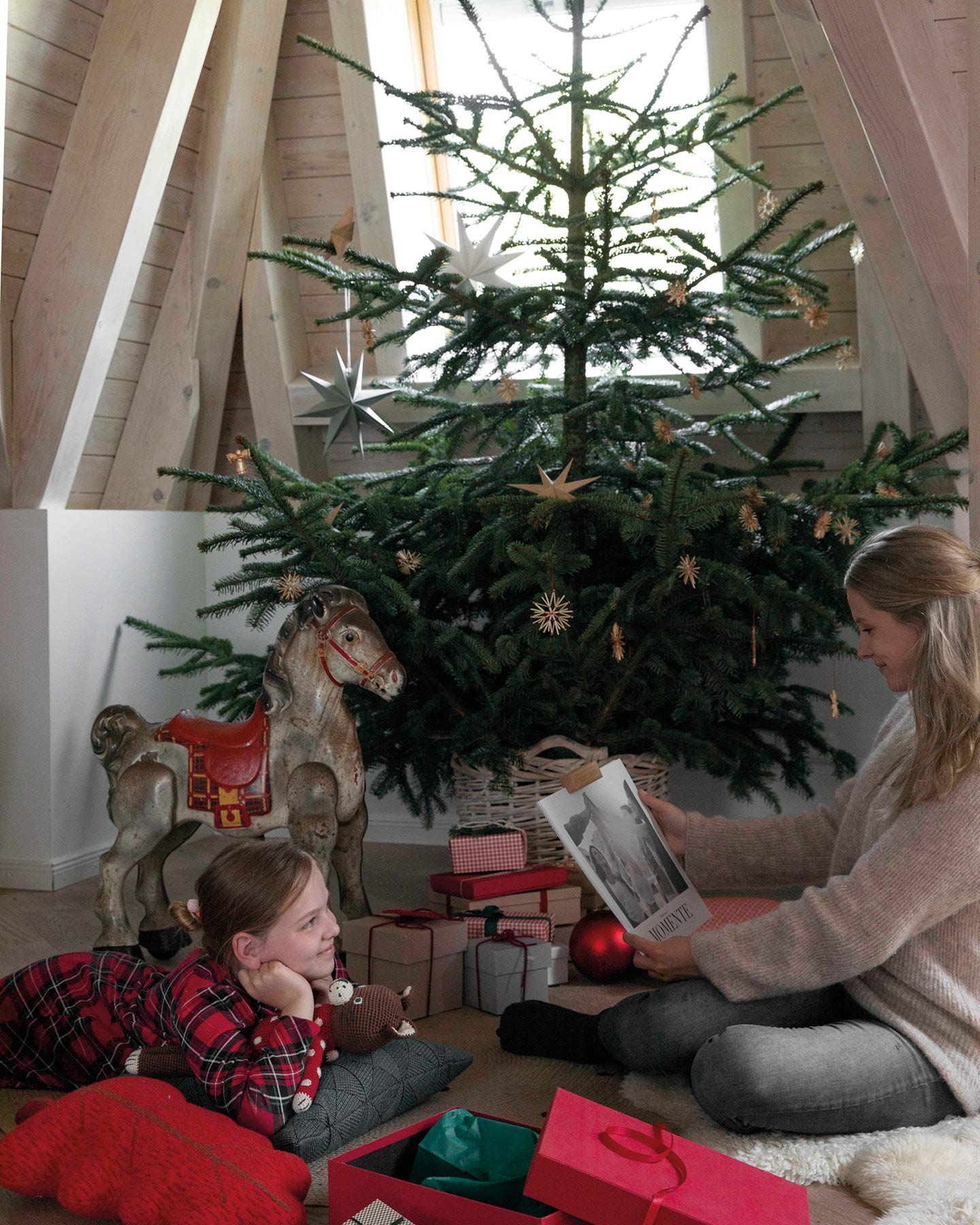 Geschwister sitzen unterm Weihnachtsbaum und packen Geschenke aus.