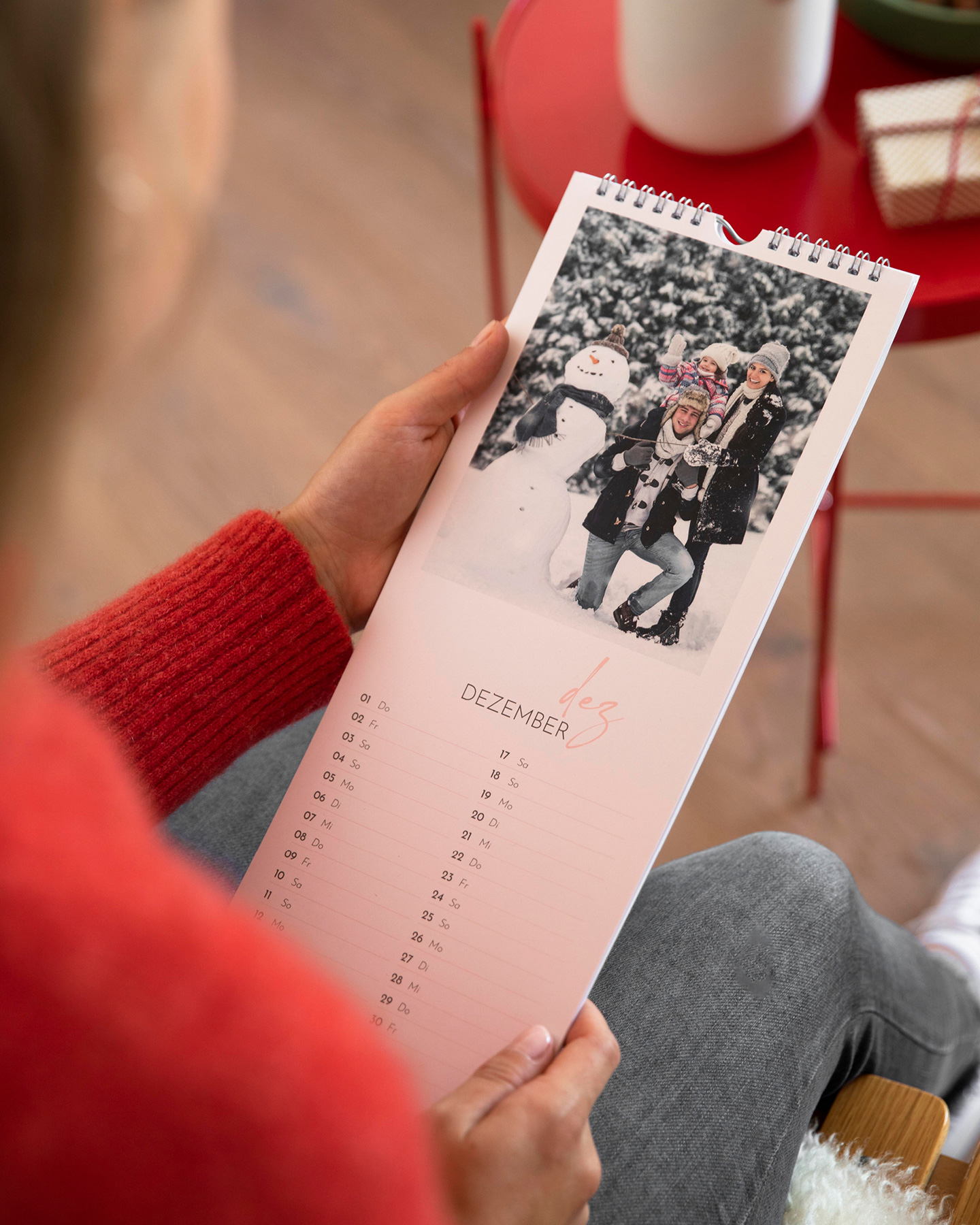 Küchenkalender mit Familienfoto wird in zwei Händen einer Frau gehalten. 