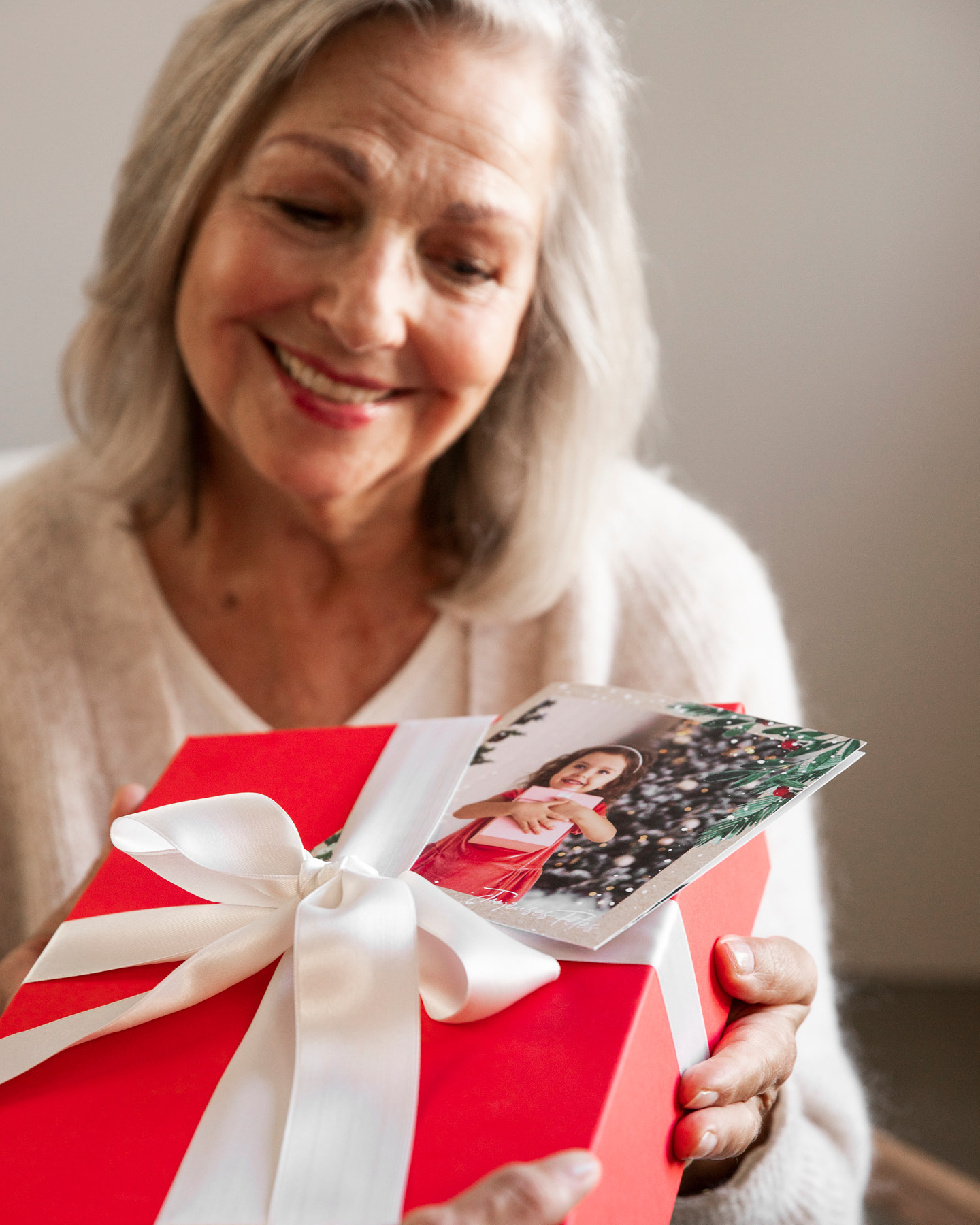 Frau mittleren Alters freut sich über Geschenk und Karte mit lustigen Weihnachtsgrüßen