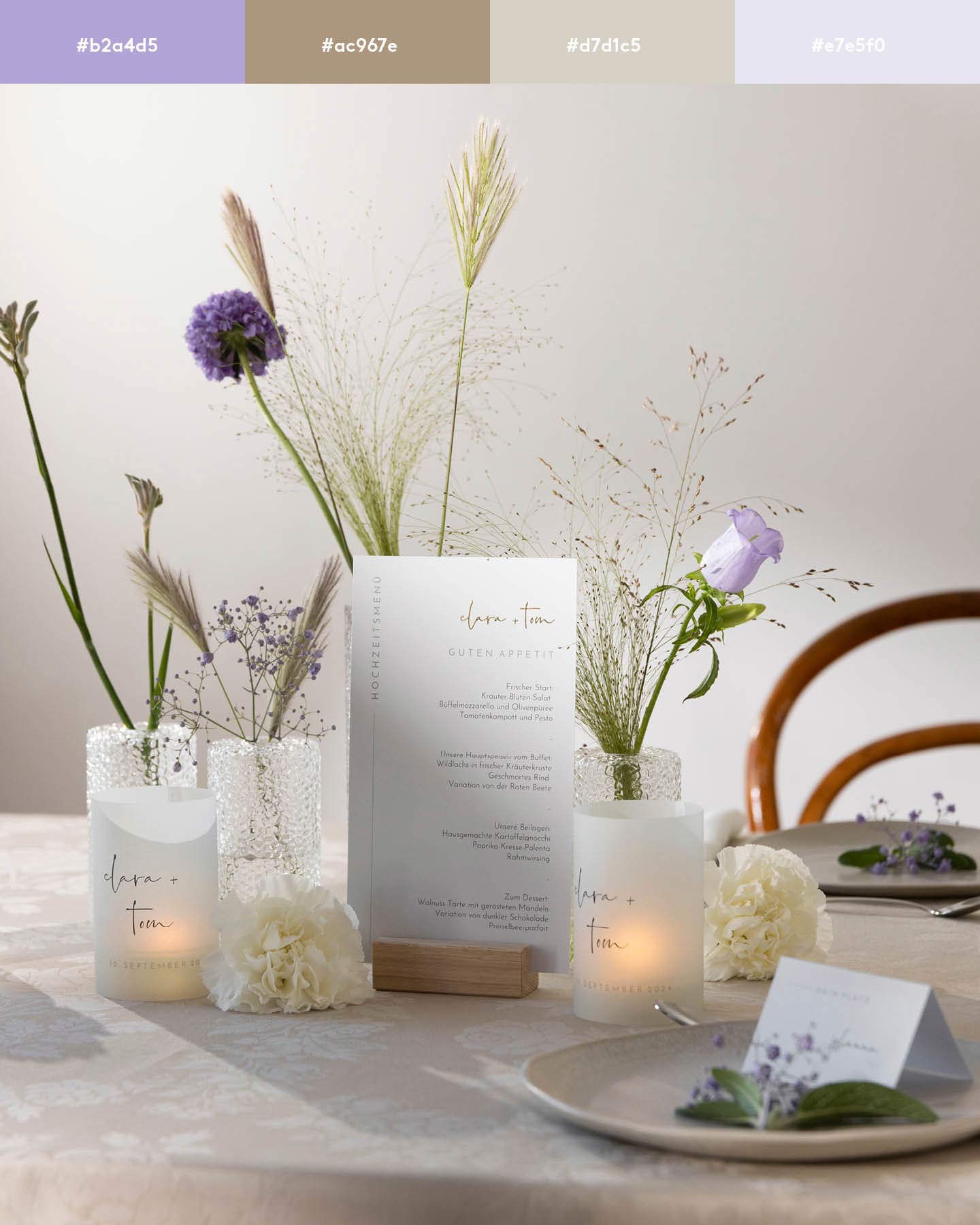 Auf einer Hochzeitstafel stehen Blumen in zarten Violet. Davor ist eine weiße Menükarte und Teelichter mit den Namen des Brautpaares.