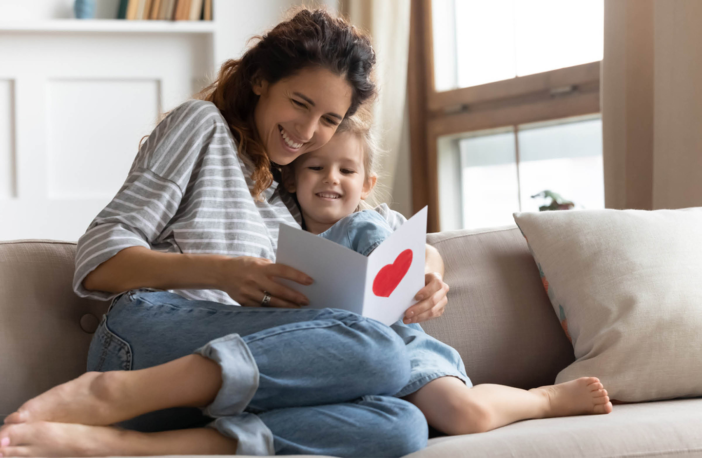 Mutter und Kind sitzen auf dem Sofa und schauen sie einen Brief an, den sie bekommen haben. 