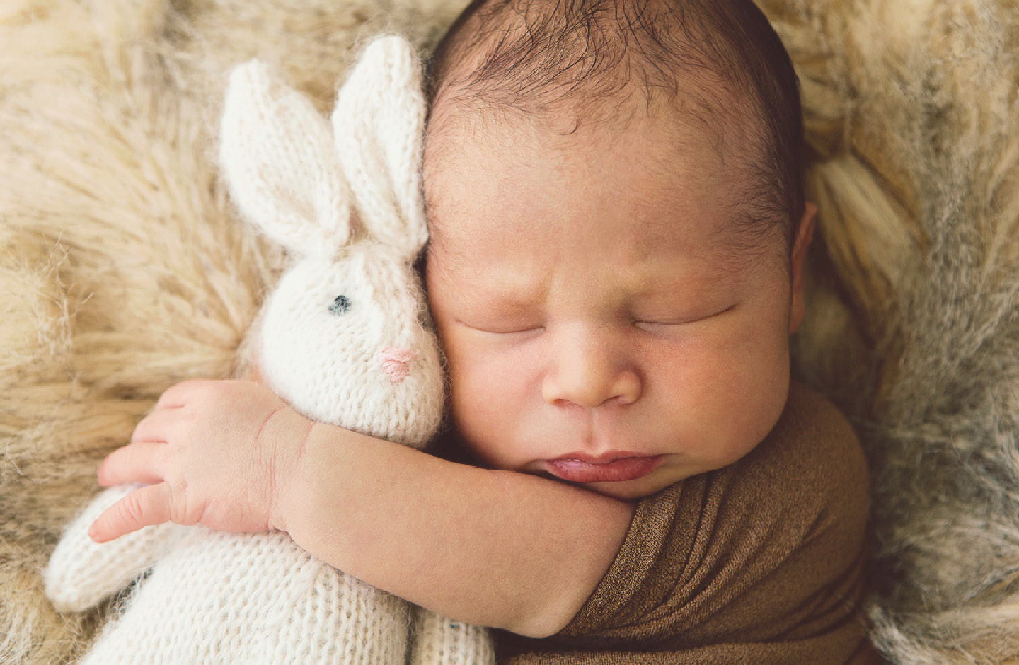 Schlafendes Baby mit Kuschelhasen im Arm