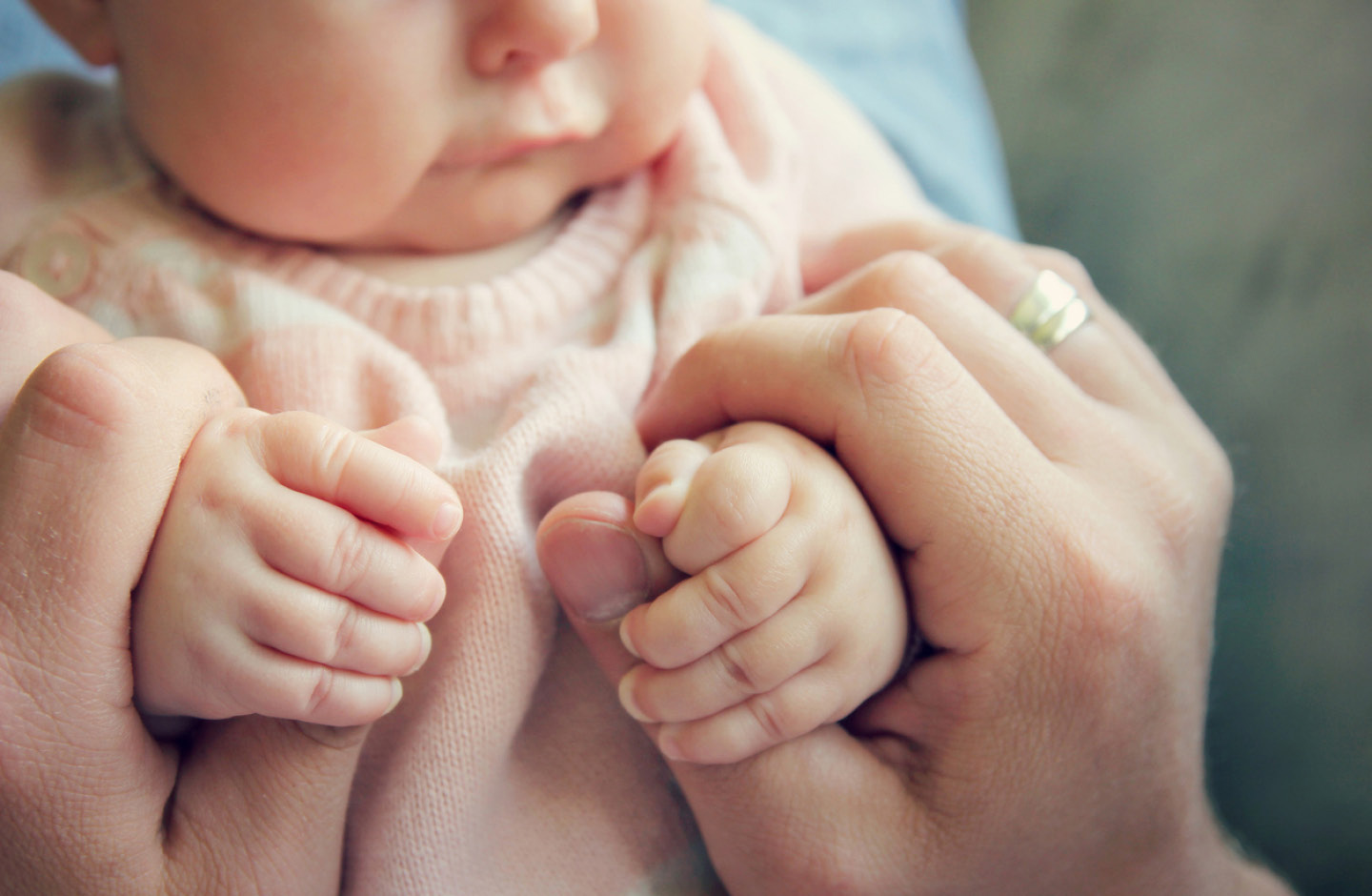 Vater hält zärtlich bei de Hände ihres Babys