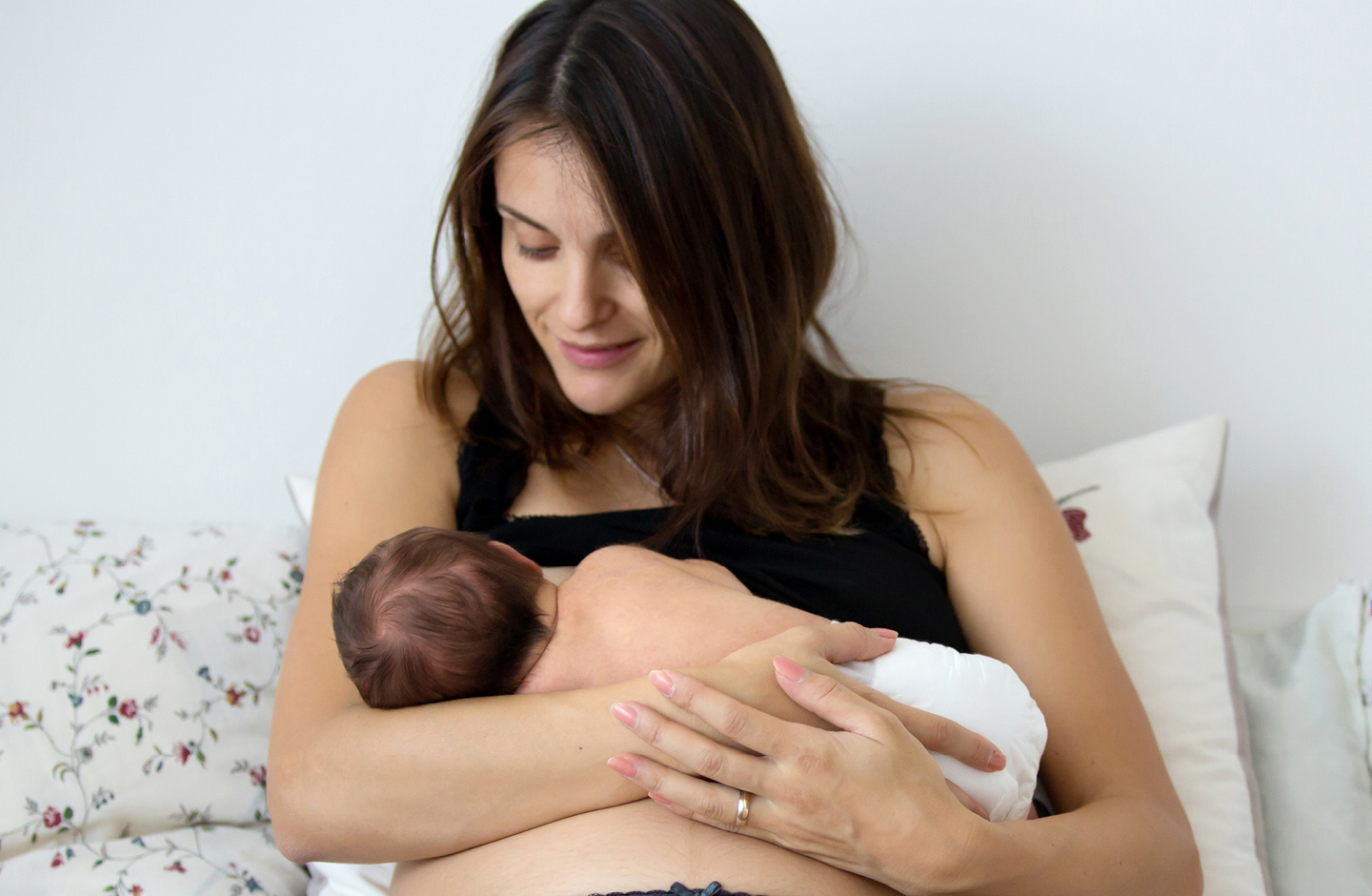 Frau hält ihr Neugebornes auf dem Arm und stillt nach der Geburt.