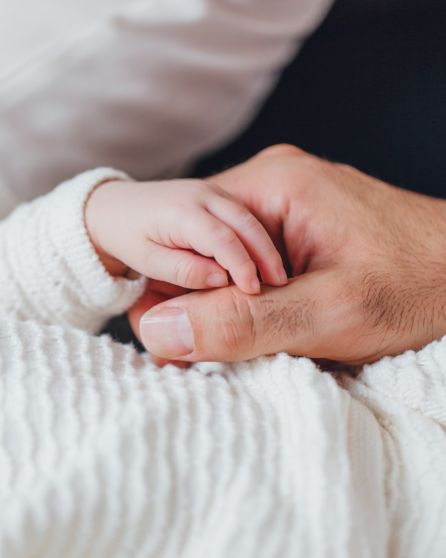 Nahaufnahme: Vater hält die winzige Hand seines Babys