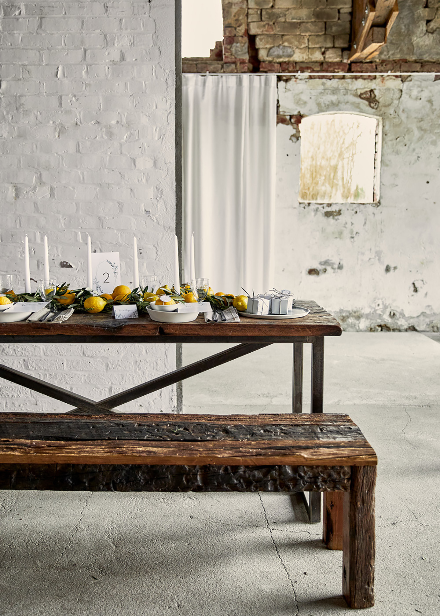 Rustikale Holzbank mit dazu passendem Tisch, dekoriert im schlichten Look mit Zitronen als Haupt-Dekoelement. Die Location ist im Shabby-Look gehalten.
