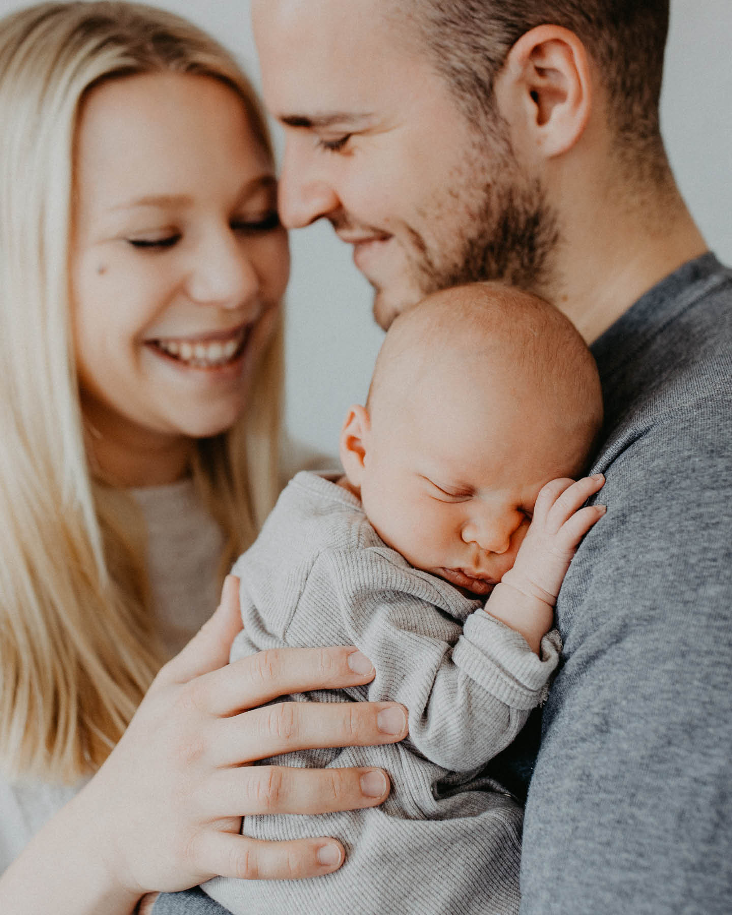 Ein Baby wird von den Eltern auf dem Arm gehalten.